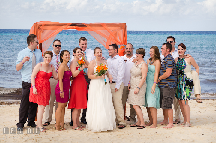 Group shot with the Bride and Groom by the orange canopy on the beach. Carnival Cruise ship destination wedding reception photos of Jessica and Chad, Cozumel Mexico by photographers of Leo Dj Photography.