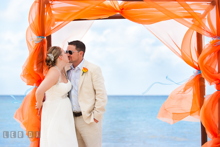 Bride and groom kissing under a canopy on the beach. Cruise ship destination wedding ceremony photos, Hotel Melia Cozumel Mexico by photographers of Leo Dj Photography.
