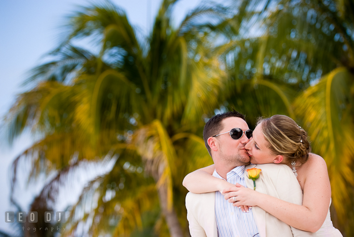 Bride and Groom kissed on the beach, by the palm trees. Carnival Cruise ship destination wedding reception photos of Jessica and Chad, Cozumel Mexico by photographers of Leo Dj Photography.