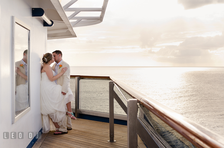 Bride and Groom kissing on the balcony outside their room. Carnival Cruise ship destination wedding reception photos of Jessica and Chad, Cozumel Mexico by photographers of Leo Dj Photography.