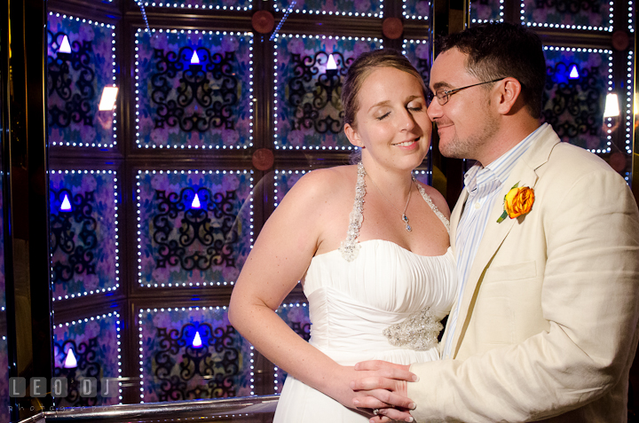 Bridge and Groom cuddling by glass elevator in the cruise ship. Carnival Cruise ship destination wedding reception photos, Cozumel Mexico by photographers of Leo Dj Photography.
