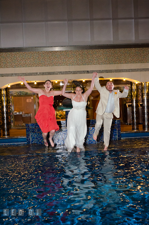 Bride, Groom and Maid of Honor starting to jump into swimming pool to trash the dress. Carnival Cruise ship destination wedding reception photos, Cozumel Mexico by photographers of Leo Dj Photography.