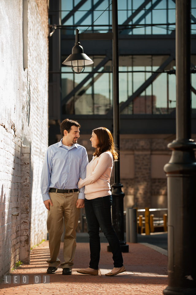 Engaged girl on a sidewalk holding her fiancé and smiling. Washington DC pre-wedding engagement photo session at Adams Morgan and the Smithsonians, by wedding photographers of Leo Dj Photography. http://leodjphoto.com