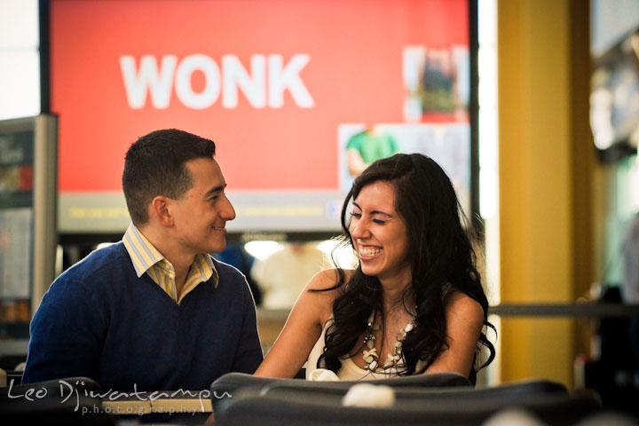 Engaged couple sitting by a restaurant table, laughing. Pre wedding engagement photo Washington DC Smithsonians museum and Ronald Reagan Washington National Airport DCA, by wedding photographer Leo Dj Photography