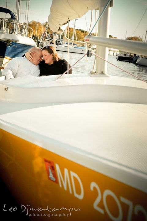 Engaged lady cuddles her fiancé in a sailboat. Annapolis Downtown USNA Pre-wedding Engagement Photographer, Leo Dj Photography