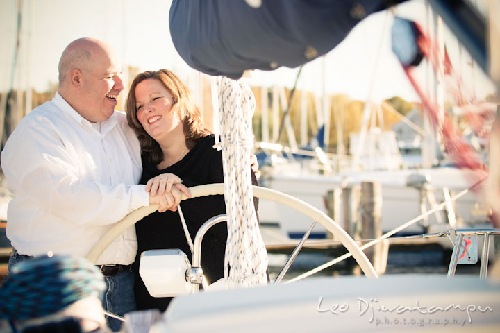 Engaged couple holding sailboat steering wheel. Annapolis Downtown USNA Pre-wedding Engagement Photographer, Leo Dj Photography