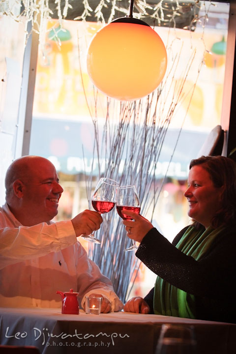 Fiancé and his fiancée clinking wine glass in a restaurant. Annapolis Downtown USNA Pre-wedding Engagement Photographer, Leo Dj Photography