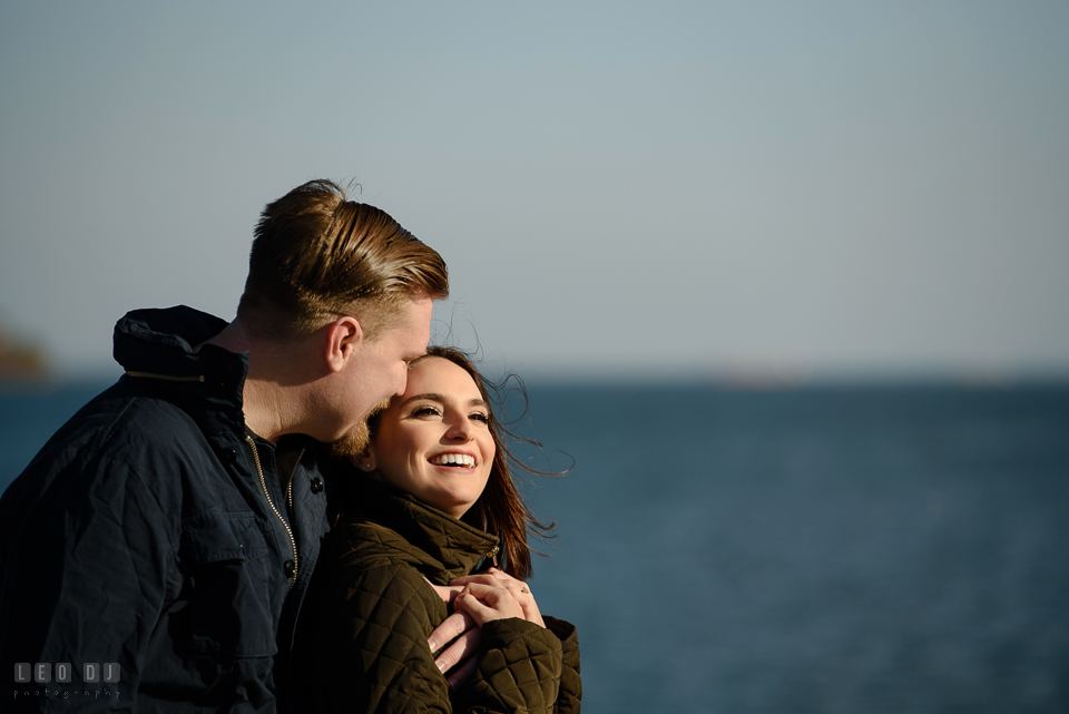 Jonas Green Park Annapolis Maryland engaged man hugging fiancée by the water photo by Leo Dj Photography.