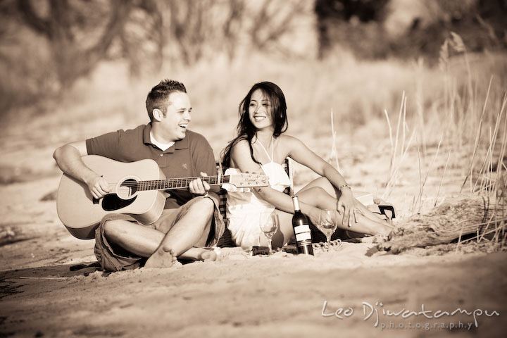 engaged couple having picnic, playing guitar, laughing. Romantic engagement session on beach Kent Island Maryland
