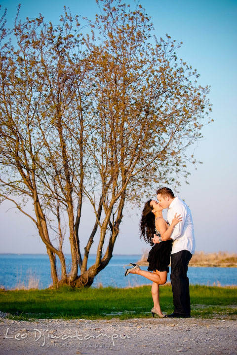 guy and girl kissing. girl lift one leg. Romantic engagement session on beach Kent Island Maryland