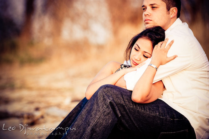 engaged couple cuddling, enjoying the sunset on the shore. Romantic engagement session on beach Kent Island Maryland