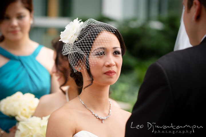 Beautiful bride looking at groom, watched by bridesmaid in the background. Falls Church Virginia 2941 Restaurant Wedding Photography