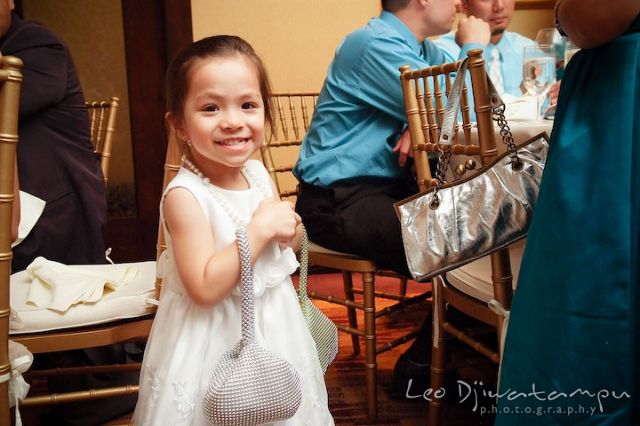 Flower girl carrying two purses and grins. Falls Church Virginia 2941 Restaurant Wedding Photographer