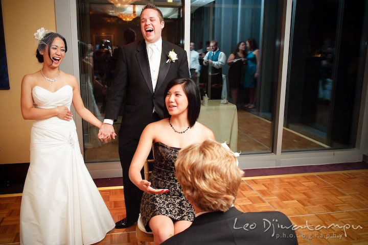 Bride and groom laughing watching guy put garter on girl. Falls Church Virginia 2941 Restaurant Wedding Photographer