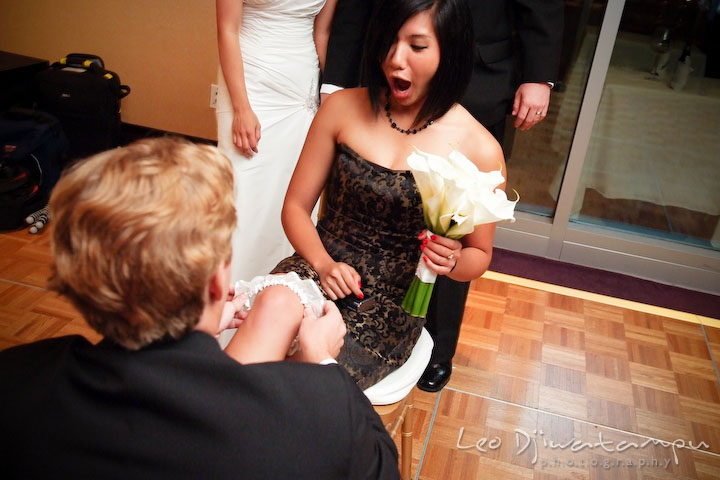 Girl suprised when guy put on garter on her leg. Falls Church Virginia 2941 Restaurant Wedding Photographer