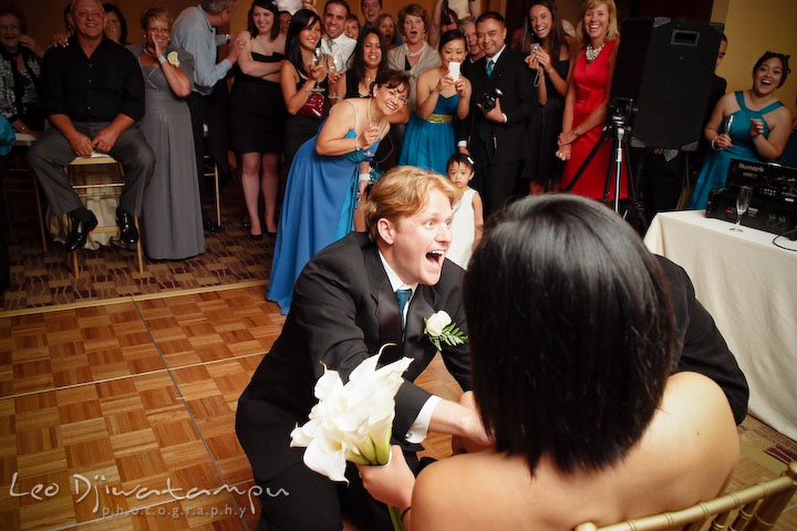 Guy laughing puting garter on girls leg, everyone looking, laughing. Falls Church Virginia 2941 Restaurant Wedding Photographer