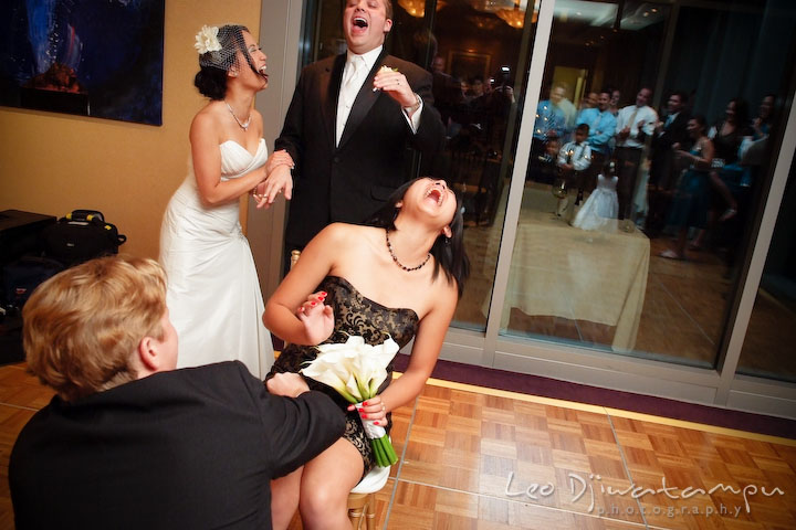 Girl laughing, ticklish, when guy puts garter on her leg. Bride and groom laughing hard. Falls Church Virginia 2941 Restaurant Wedding Photographer