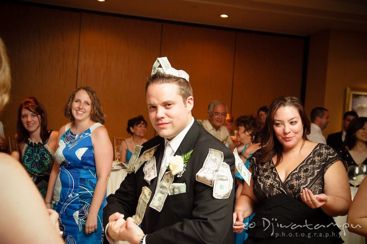 Groom showing all the dollar bills on him, macho guy pose. Other guests laughing . Falls Church Virginia 2941 Restaurant Wedding Photographer