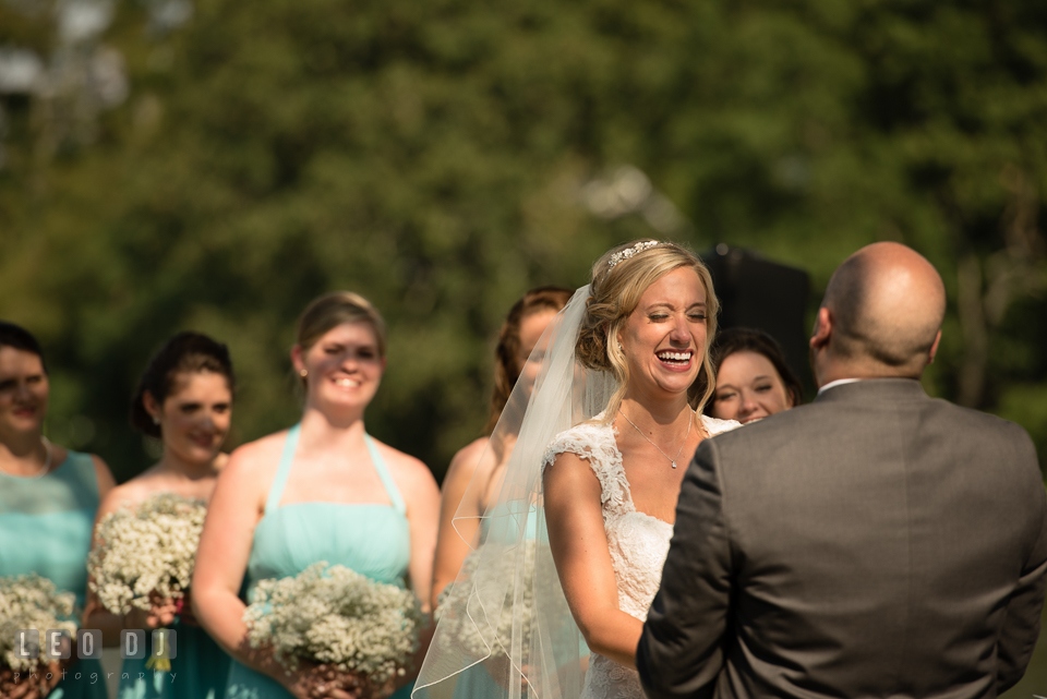 The Oaks Waterfront Inn Bride laughing while Groom reciting vows during the ceremony Flowers photo by Leo Dj Photography