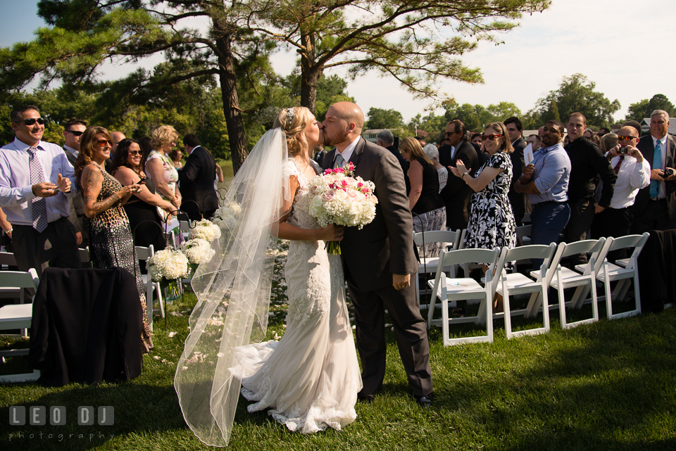 The Oaks Waterfront Inn Bride and Groom kissing as they walk out of the aisle during ceremony recessional photo by Leo Dj Photography