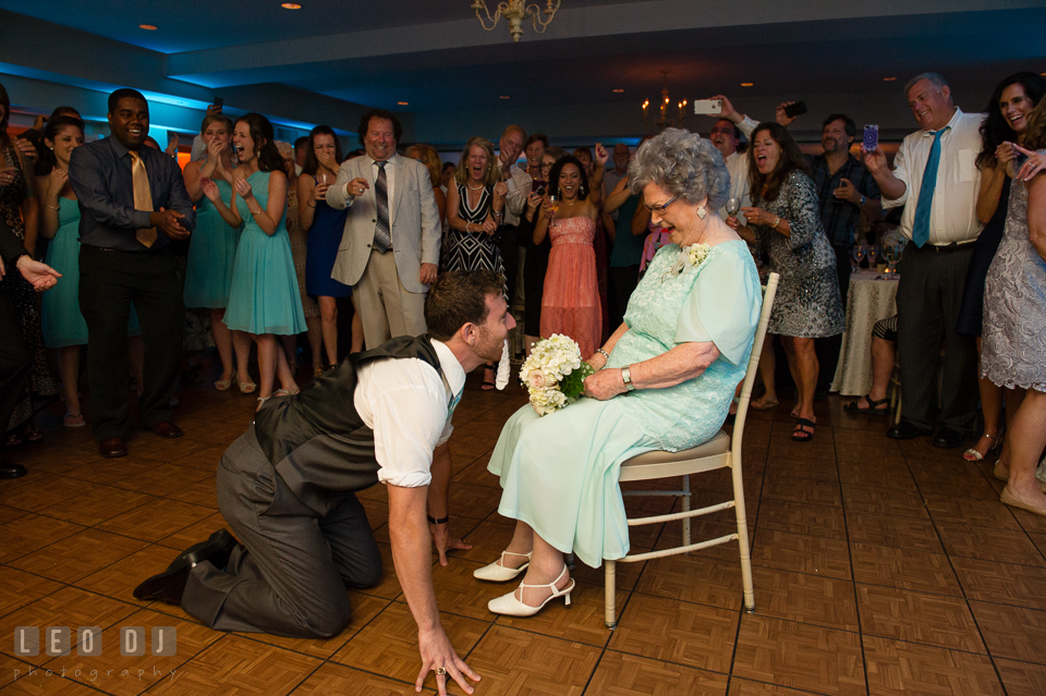 The Oaks Waterfront Inn Groomsman crawling with garter in front of grandma photo by Leo Dj Photography