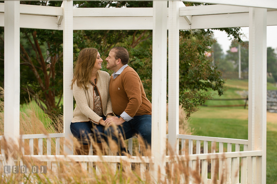 Engaged couple sitting underneath a gazebo, cuddling and laughing. Eastern Shore Maryland pre-wedding engagement photo session at St Michaels MD, by wedding photographers of Leo Dj Photography. http://leodjphoto.com