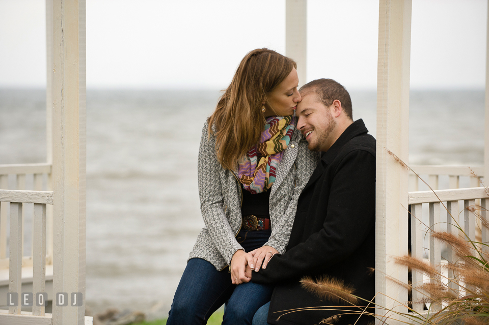 Engaged girl kissing her fiancé, under the gazebo by the water. Eastern Shore Maryland pre-wedding engagement photo session at St Michaels MD, by wedding photographers of Leo Dj Photography. http://leodjphoto.com