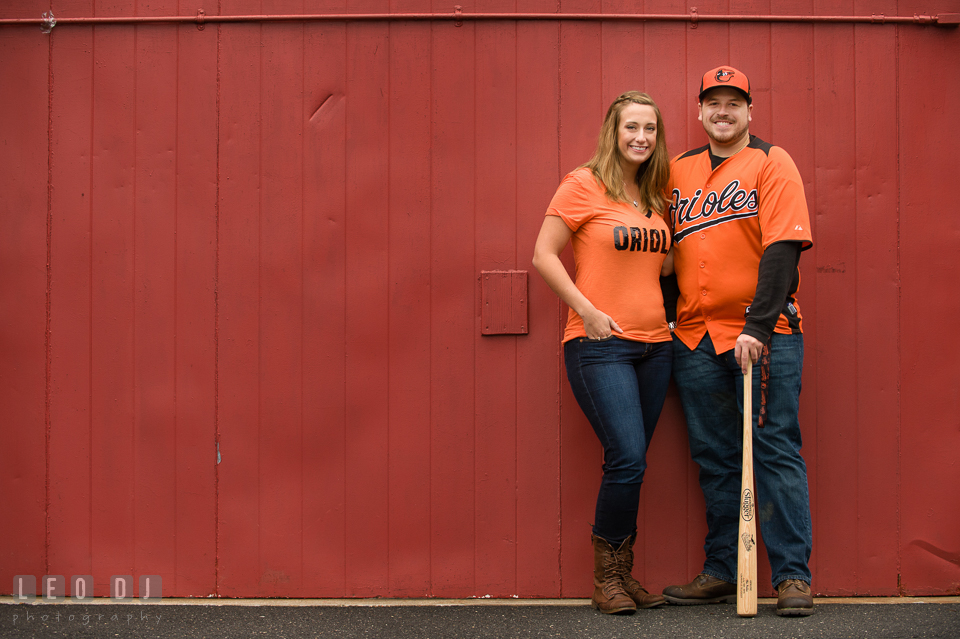 Engaged couple posing with Baltimore Orioles jersey, hat, and a Louisville Slugger baseball bat. Eastern Shore Maryland pre-wedding engagement photo session at St Michaels MD, by wedding photographers of Leo Dj Photography. http://leodjphoto.com