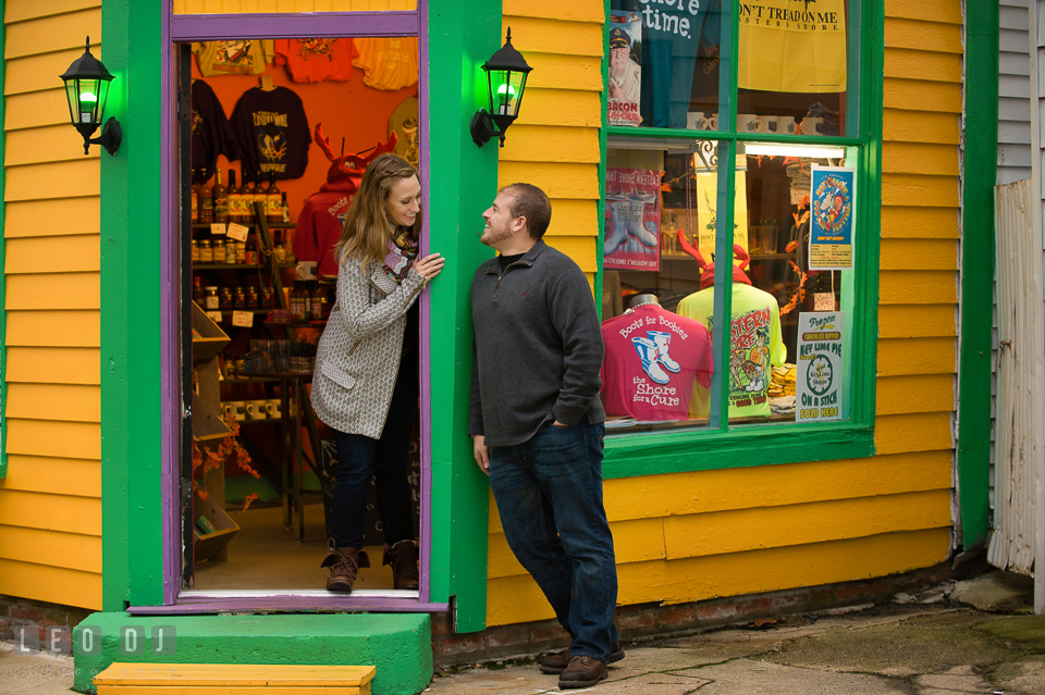 Engaged girl and man looking at each other by a door at at colorful gift shop. Eastern Shore Maryland pre-wedding engagement photo session at St Michaels MD, by wedding photographers of Leo Dj Photography. http://leodjphoto.com