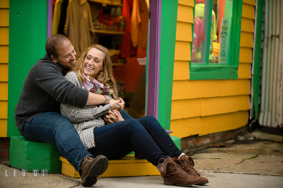 Engaged girl snuggled with her fiancé in front of a gift shop. Eastern Shore Maryland pre-wedding engagement photo session at St Michaels MD, by wedding photographers of Leo Dj Photography. http://leodjphoto.com