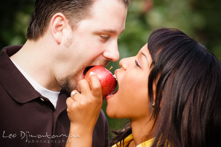 Engaged guy and girl eating apple together. Engagement pre-wedding photo session fruit tree farm barn flower garden by Leo Dj Photography