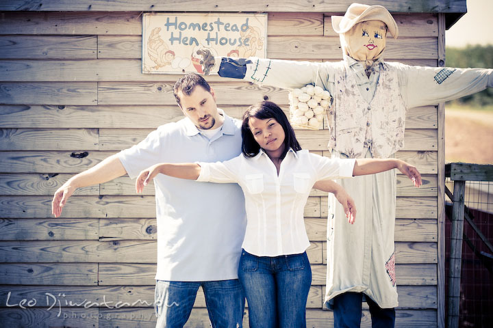 Engaged couple copying or mimicking a scarecrow posture. Engagement pre-wedding photo session fruit tree farm barn flower garden by Leo Dj Photography