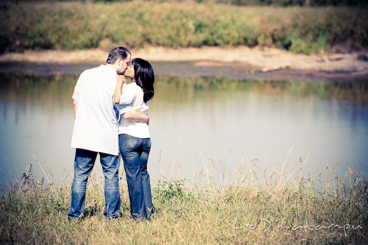 Engaged couple standing by a pond and kissed. Engagement pre-wedding photo session fruit tree farm barn flower garden by Leo Dj Photography
