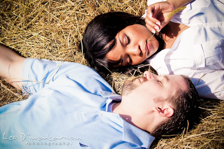 Engaged guy and girl laying on the hay. Engagement pre-wedding photo session fruit tree farm barn flower garden by Leo Dj Photography