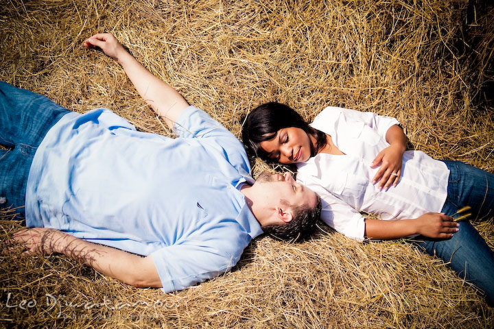 Engaged man and woman laying on the hay. Engagement pre-wedding photo session fruit tree farm barn flower garden by Leo Dj Photography