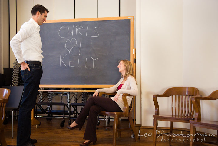 Engaged girl smiling to her fiancé for the writing on blackboard. Pre-wedding engagement photo session at Washington College and Chestertown, Maryland, by wedding photographer Leo Dj Photography.