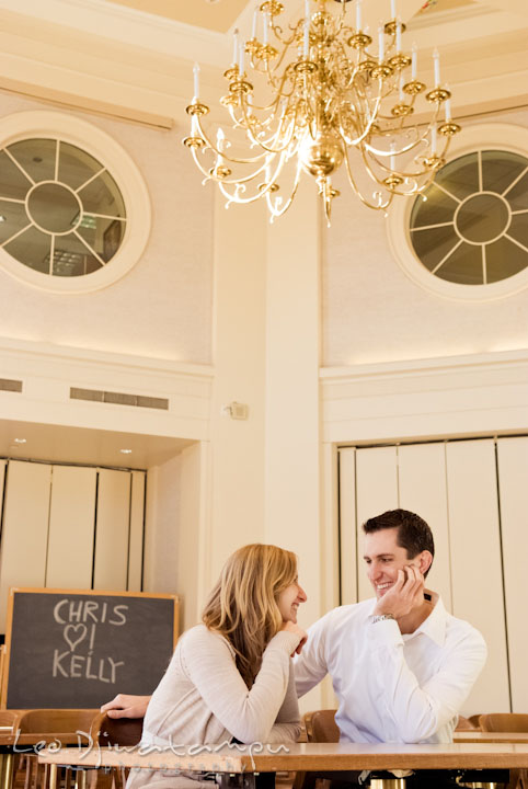 Engaged couple looking at each other, love writing on blackboard. Pre-wedding engagement photo session at Washington College and Chestertown, Maryland, by wedding photographer Leo Dj Photography.