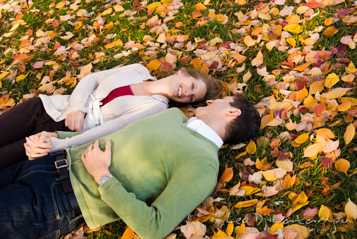Engaged guy lying on ground filled with fall leaves with his fiancée. Pre-wedding engagement photo session at Washington College and Chestertown, Maryland, by wedding photographer Leo Dj Photography.