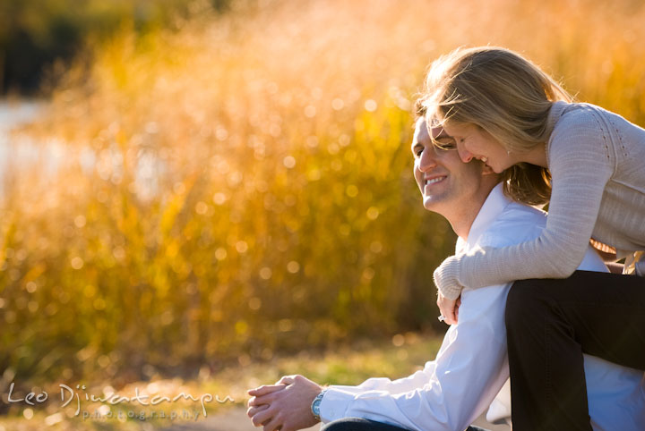 Engaged girl hugging her fiance, sitting on bench. Pre-wedding engagement photo session at Washington College and Chestertown, Maryland, by wedding photographer Leo Dj Photography.