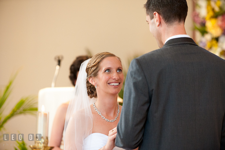 Bride smiled while putting on ring on Groom's finger. St Andrews United Methodist wedding photos at Annapolis, Eastern Shore, Maryland by photographers of Leo Dj Photography.