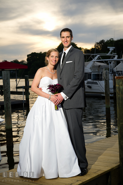 Bride and Groom posing on the boat pier during sunset. Yellowfin Restaurant wedding reception photos at Annapolis, Eastern Shore, Maryland by photographers of Leo Dj Photography.