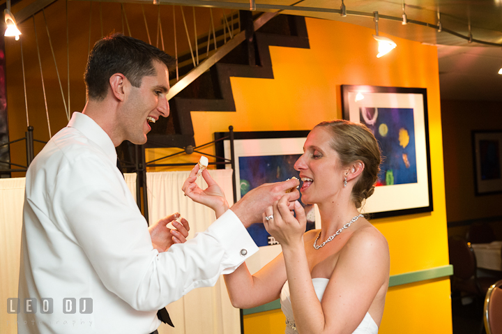 Bride and Groom feeding each other the wedding cake. Yellowfin Restaurant wedding reception photos at Annapolis, Eastern Shore, Maryland by photographers of Leo Dj Photography.