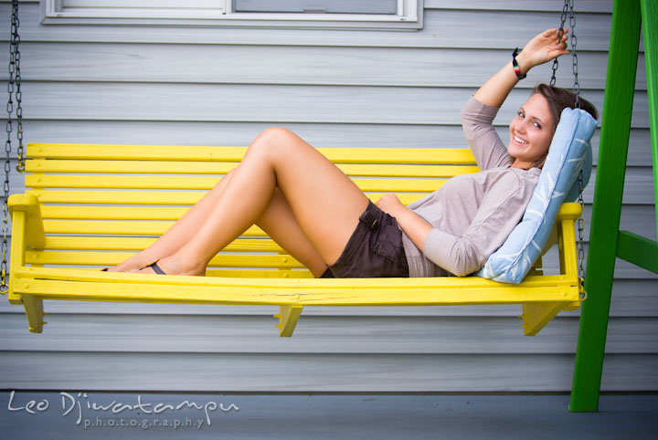 Girl lounging on yellow swing. Eastern Shore, Maryland, Kent Island High School senior portrait session by photographer Leo Dj Photography.