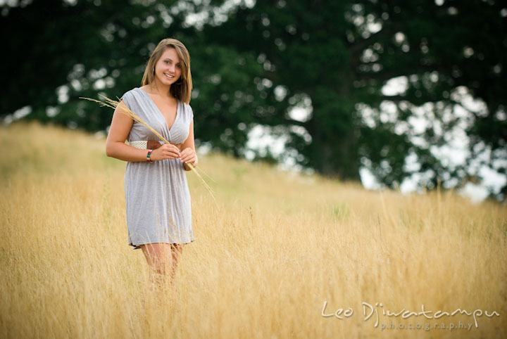 Girl holding grass straws in a tall grass field. Eastern Shore, Maryland, Kent Island High School senior portrait session by photographer Leo Dj Photography.