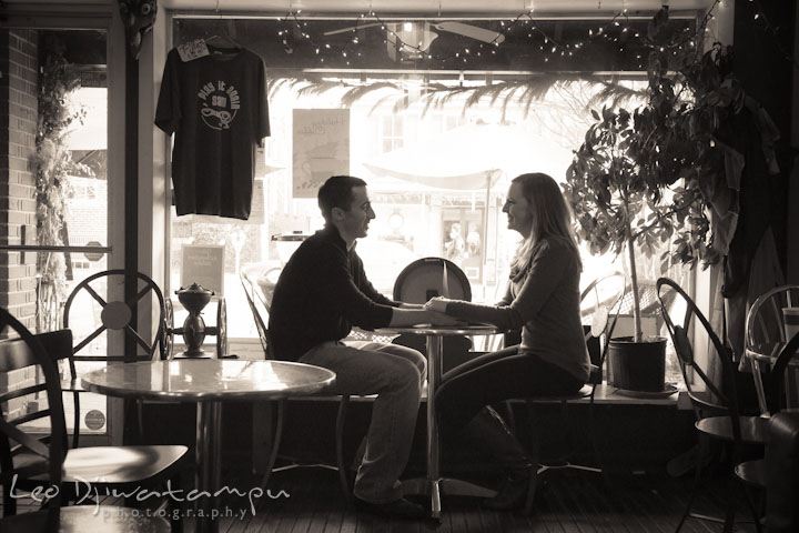 Engaged couple sitting inside coffee shop, holding hands. Chestertown Maryland and Washington College Pre-Wedding Engagement Session Photographer, Leo Dj Photography