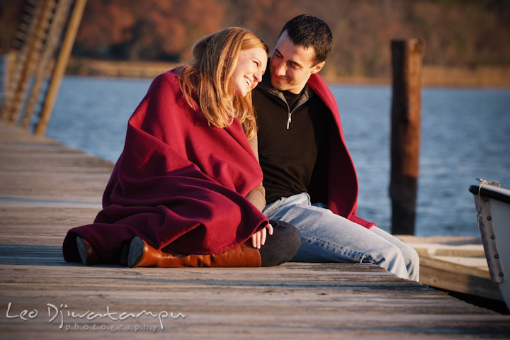 Engaged couple sitting on a pier, smiling. Chestertown Maryland and Washington College Pre-Wedding Engagement Session Photographer, Leo Dj Photography