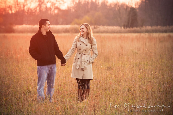 Engaged girl holding hands and looking at her fiancé in a meadow. Chestertown Maryland and Washington College Pre-Wedding Engagement Session Photographer, Leo Dj Photography