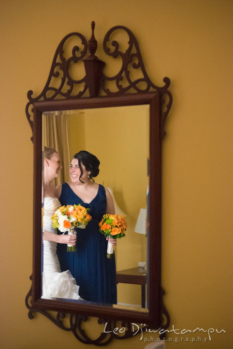 Reflection of bride and maid of honor laughing in the mirror. The Tidewater Inn Wedding, Easton Maryland, getting ready photo coverage of Kelsey and Jonnie by wedding photographers of Leo Dj Photography.