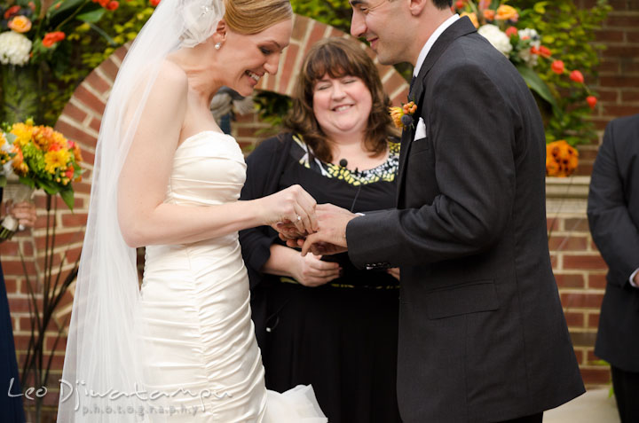 Bride putting wedding band on groom's finger. The Tidewater Inn Wedding, Easton Maryland, ceremony photo coverage of Kelsey and Jonnie by wedding photographers of Leo Dj Photography.