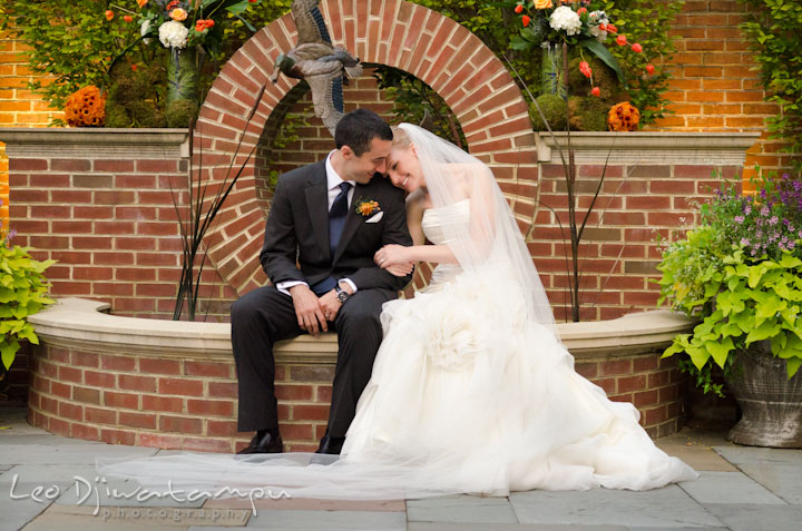 Bride and groom cuddling by the water fountain. The Tidewater Inn Wedding, Easton Maryland, ceremony photo coverage of Kelsey and Jonnie by wedding photographers of Leo Dj Photography.